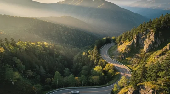 Vue panoramique d'une route sinueuse traversant un parc national d'Hokkaido avec montagnes et forêts